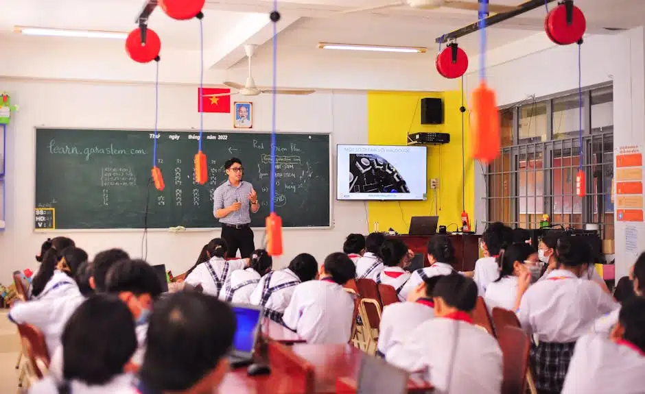 Un enseignant anime une leçon interactive dans une salle de classe vivante, face à des élèves attentifs.