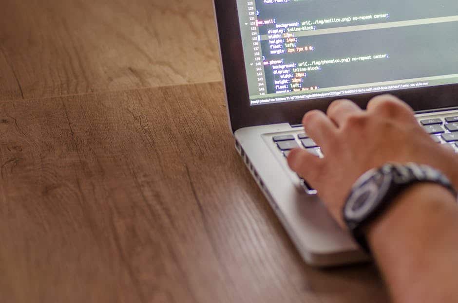 Gros plan d'une personne codant sur un ordinateur portable, illustrant le développement web et la programmation.