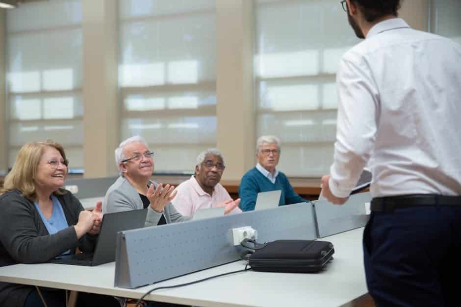 Des seniors suivent un cours d'informatique animé par un formateur, en salle de classe.