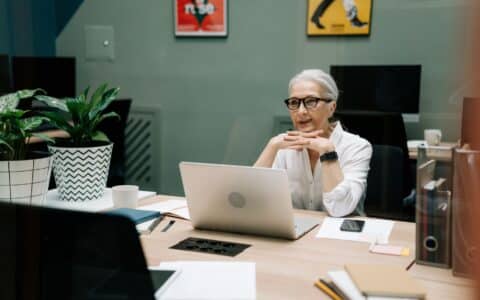 Quadragenaire souriante preparant sa reconversion professionnelle devant son ordinateur