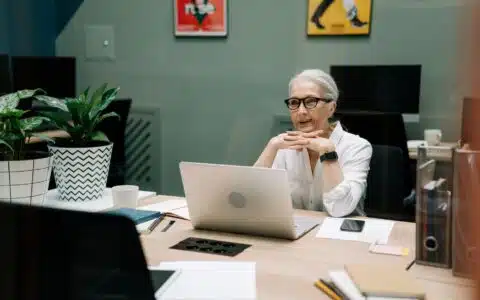 Quadragenaire souriante preparant sa reconversion professionnelle devant son ordinateur