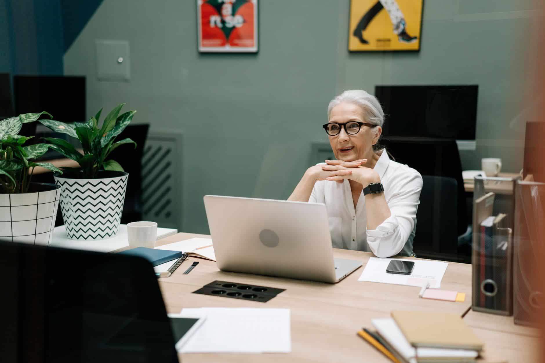 Quadragénaire souriante préparant sa reconversion professionnelle devant son ordinateur