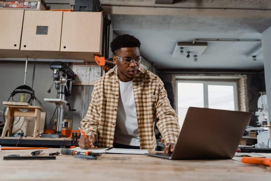 Artisan menuisier consultant ses mails sur un ordinateur portable dans son atelier