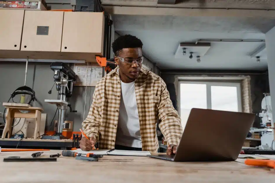 Artisan menuisier consultant ses mails sur un ordinateur portable dans son atelier