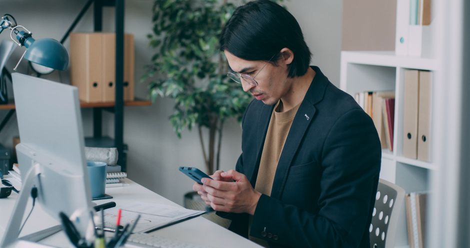 Jeune homme travaillant sur ordinateur et smartphone dans un bureau
