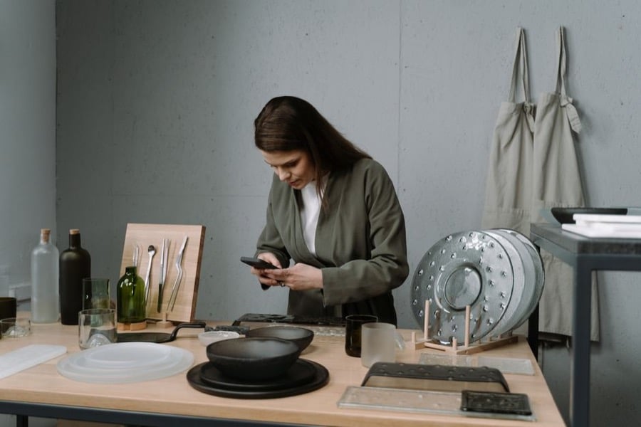 Artisane photographiant ses créations avec son téléphone dans son atelier