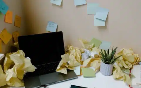 Bureau envahi de papiers froissés et de notes autocollantes, image de la surcharge d une boîte mail