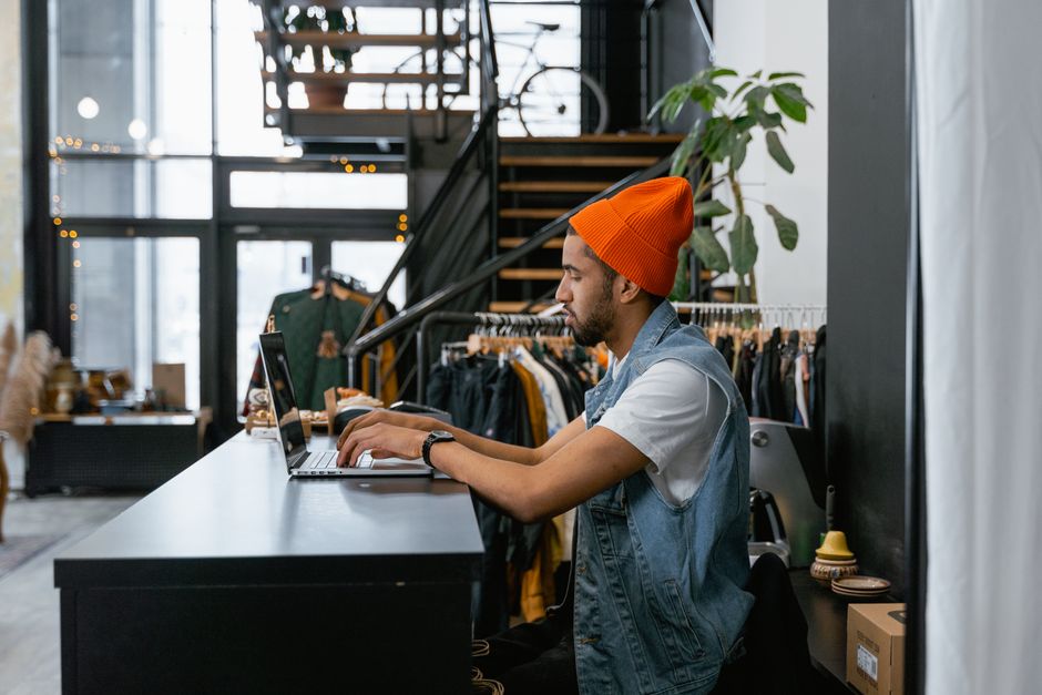 Commerçante qui prépare une tâche sur ordinateur portable au comptoir de sa boutique
