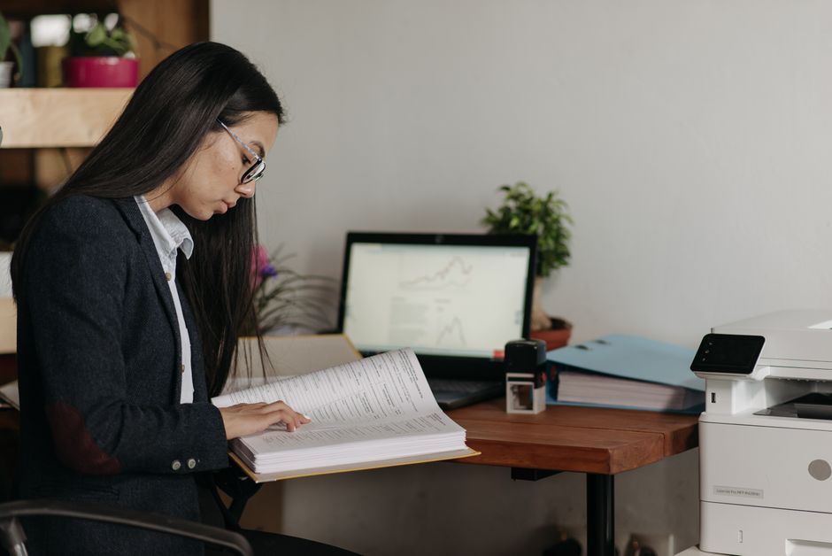 Femme qui relit des documents imprimés à son bureau avant validation