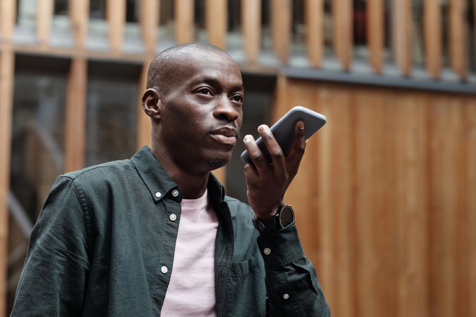 Homme qui dicte une commande vocale à son smartphone en pleine rue