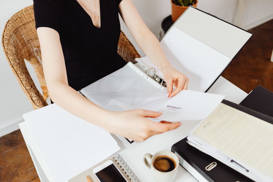 Professionnelle qui classe ses documents à son bureau, téléphone et café à portée de main