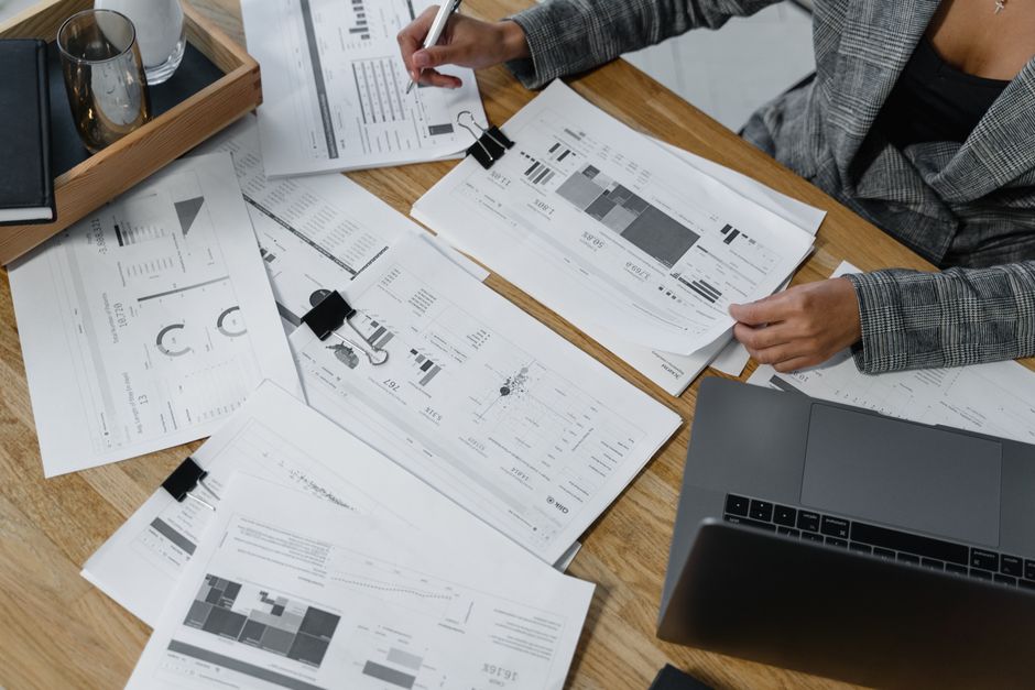 Analyse de tableaux financiers imprimés à côté d'un ordinateur portable