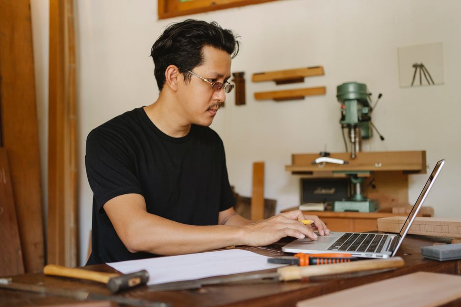 Artisan menuisier qui travaille sur son ordinateur portable dans son atelier
